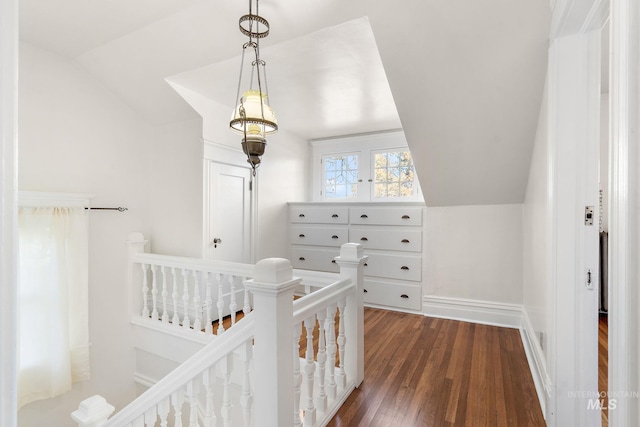 interior space with dark wood-style floors, a crib, vaulted ceiling, and baseboards