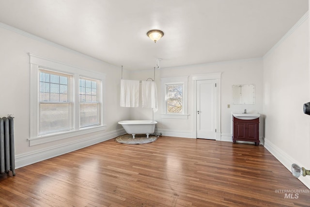 interior space featuring crown molding, radiator heating unit, wood finished floors, and baseboards