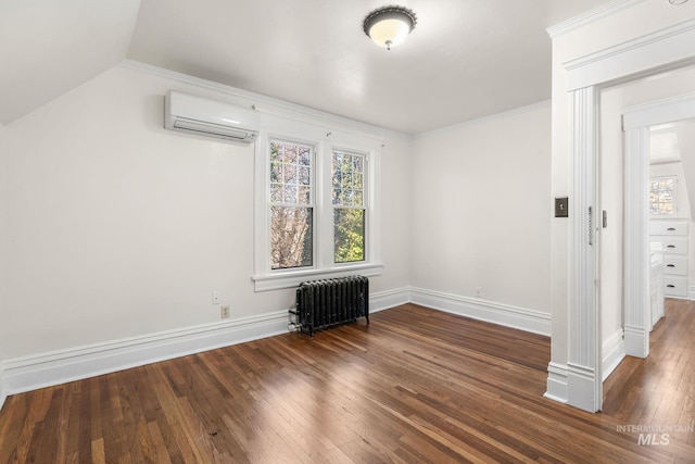 spare room with radiator, wood-type flooring, ornamental molding, a wall mounted air conditioner, and baseboards