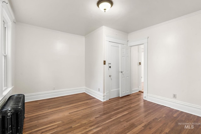 empty room with radiator, baseboards, ornamental molding, and wood finished floors