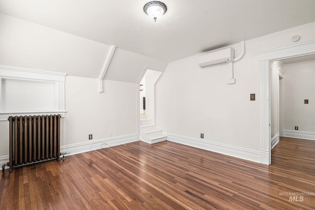 bonus room featuring vaulted ceiling, radiator heating unit, a wall unit AC, and wood finished floors