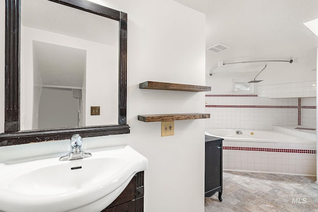 full bath featuring a relaxing tiled tub, visible vents, vanity, and walk in shower