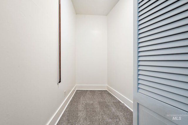 unfurnished room with baseboards and dark carpet