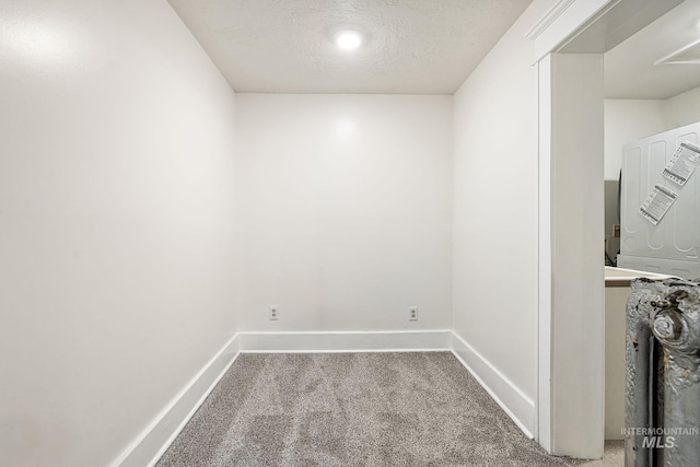 laundry room with a textured ceiling, carpet floors, and baseboards