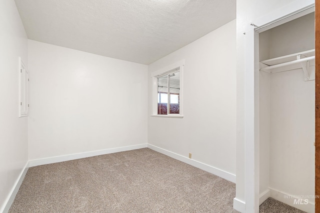 unfurnished bedroom featuring a textured ceiling, carpet flooring, and baseboards