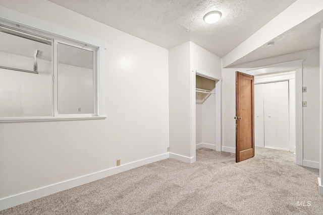 unfurnished bedroom featuring carpet floors, a closet, baseboards, and a textured ceiling