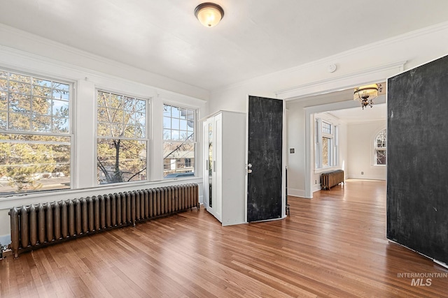 spare room with ornamental molding, radiator, and wood finished floors