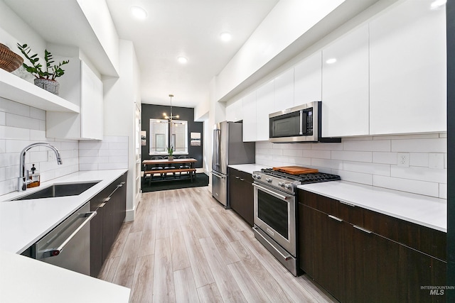 kitchen featuring appliances with stainless steel finishes, dark brown cabinets, pendant lighting, sink, and white cabinetry