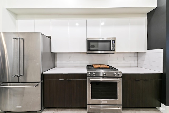 kitchen with white cabinetry, dark brown cabinetry, tasteful backsplash, and appliances with stainless steel finishes