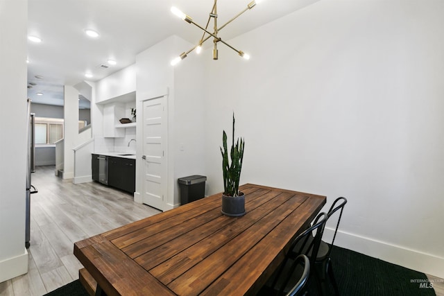 dining area with light hardwood / wood-style floors, an inviting chandelier, and sink