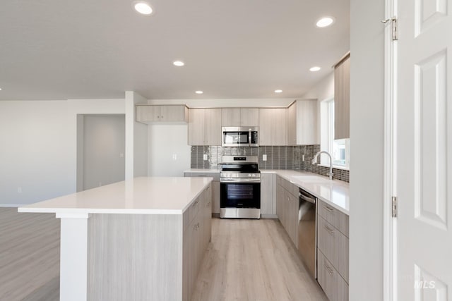 kitchen featuring backsplash, sink, light hardwood / wood-style floors, appliances with stainless steel finishes, and a kitchen island