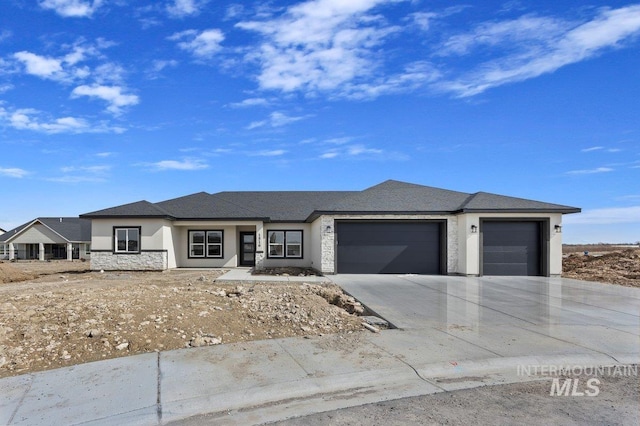 prairie-style house with a garage, stone siding, concrete driveway, and stucco siding