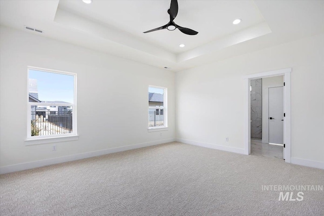 unfurnished room with ceiling fan, recessed lighting, light colored carpet, baseboards, and a tray ceiling