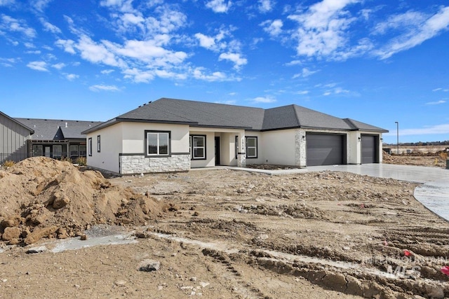 view of front of home featuring a garage, stone siding, concrete driveway, and stucco siding