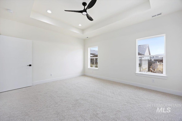 unfurnished room featuring recessed lighting, light carpet, visible vents, baseboards, and a tray ceiling