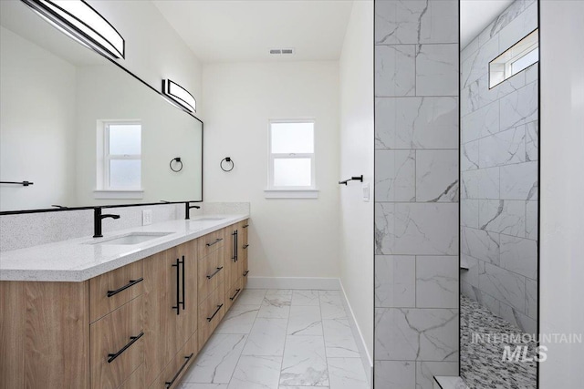 full bathroom featuring marble finish floor, double vanity, a sink, and baseboards