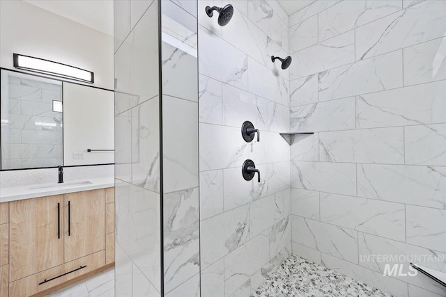 full bathroom featuring tiled shower and vanity