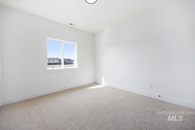 spare room with carpet, visible vents, and baseboards