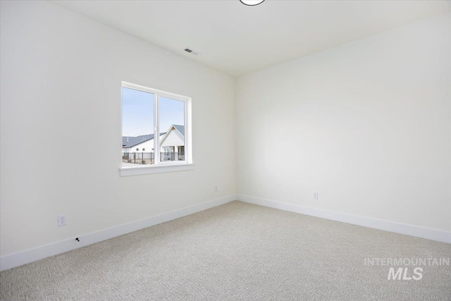 spare room featuring light carpet, visible vents, and baseboards