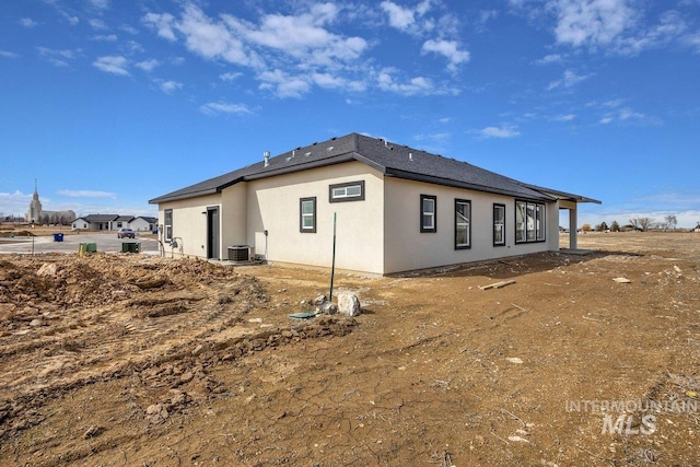 rear view of house with central air condition unit and stucco siding