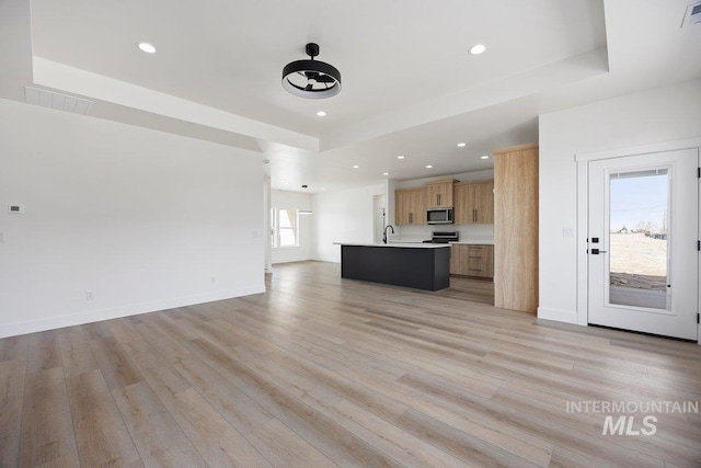 unfurnished living room featuring light wood finished floors, recessed lighting, visible vents, and baseboards