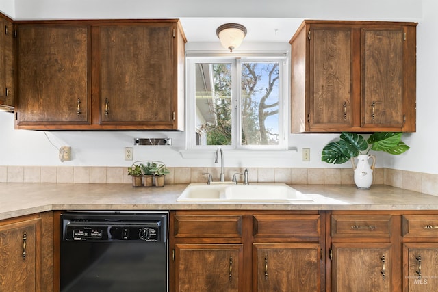 kitchen featuring light countertops, black dishwasher, and a sink