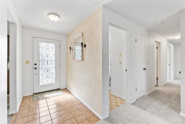 foyer with light tile patterned flooring, plenty of natural light, light colored carpet, and a textured ceiling