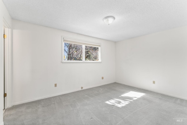 spare room with baseboards, carpet floors, and a textured ceiling