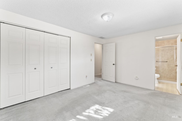 unfurnished bedroom featuring baseboards, carpet floors, a closet, a textured ceiling, and connected bathroom