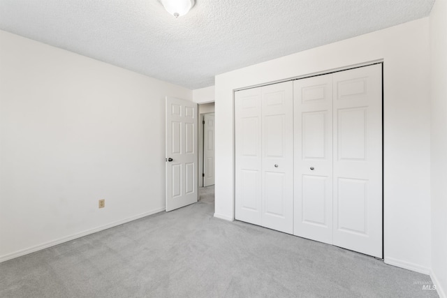 unfurnished bedroom featuring a closet, baseboards, carpet, and a textured ceiling