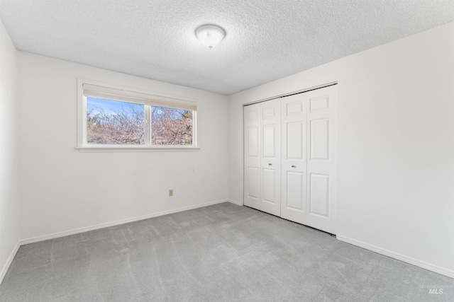 unfurnished bedroom featuring a closet, baseboards, a textured ceiling, and carpet flooring