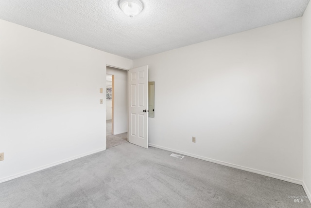 carpeted empty room featuring visible vents, baseboards, and a textured ceiling