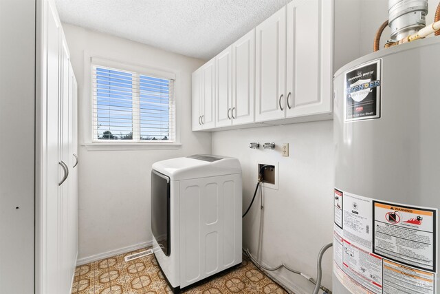 clothes washing area featuring baseboards, washer / clothes dryer, cabinet space, a textured ceiling, and gas water heater