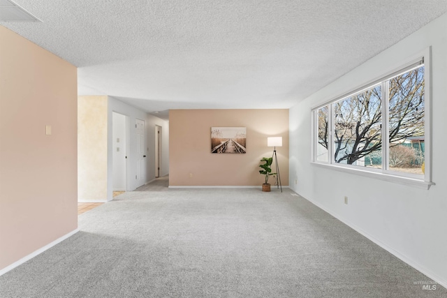 carpeted spare room featuring baseboards and a textured ceiling