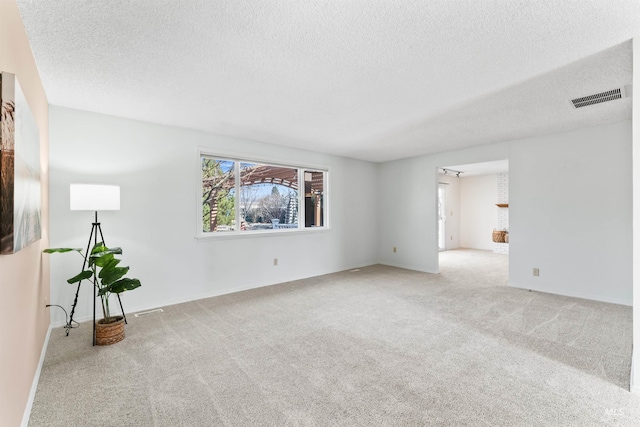 empty room with visible vents, baseboards, carpet, and a textured ceiling