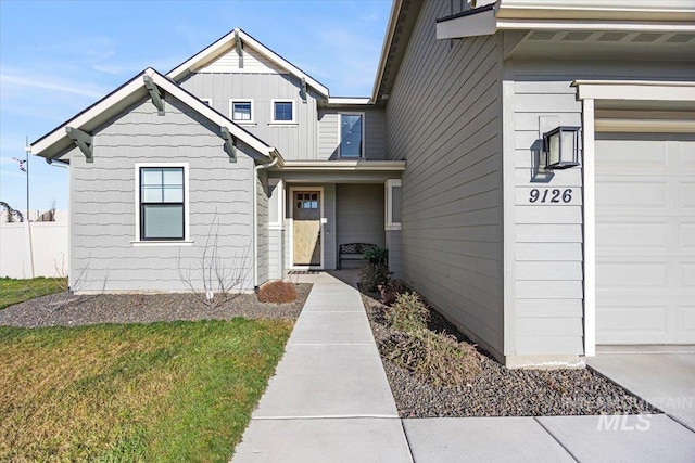 view of exterior entry with a garage and a lawn