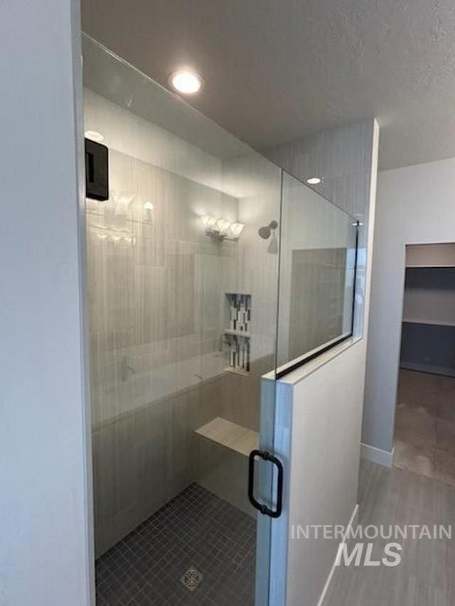 bathroom featuring a shower stall, baseboards, and a textured ceiling