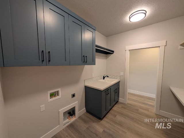 laundry room featuring washer hookup, cabinet space, light wood-style floors, a sink, and electric dryer hookup