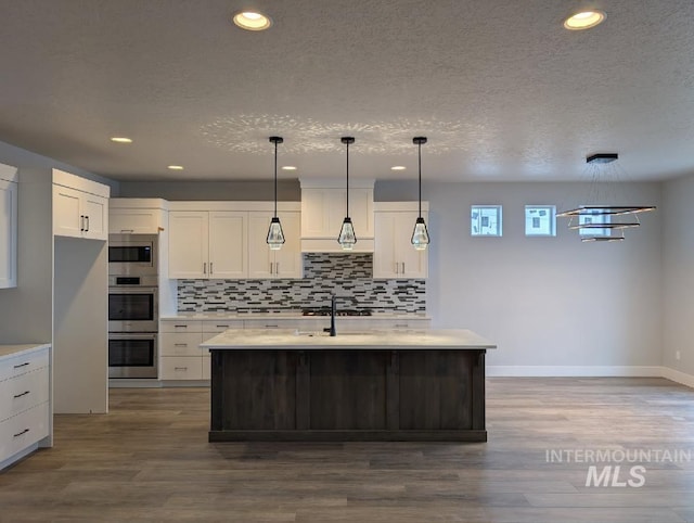 kitchen with stainless steel appliances, tasteful backsplash, light countertops, and dark wood finished floors