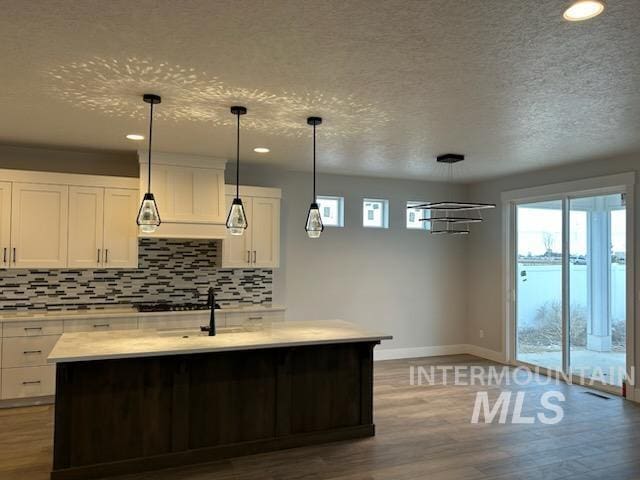 kitchen with light countertops, wood finished floors, white cabinetry, and decorative backsplash