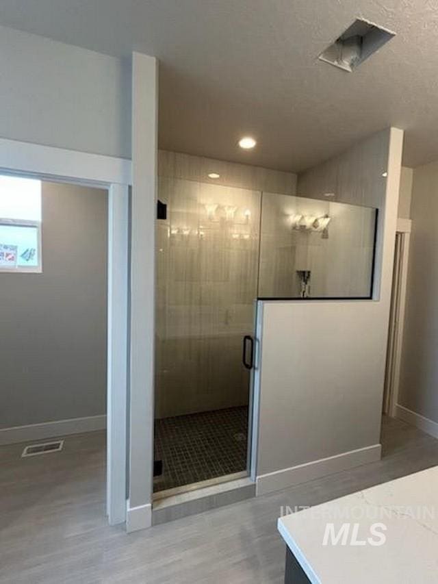 full bath featuring baseboards, visible vents, wood finished floors, a textured ceiling, and a shower stall