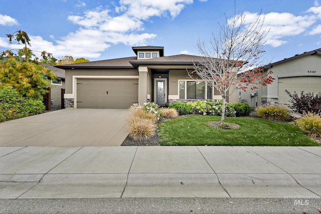 prairie-style house featuring a front yard, a garage, driveway, and stucco siding