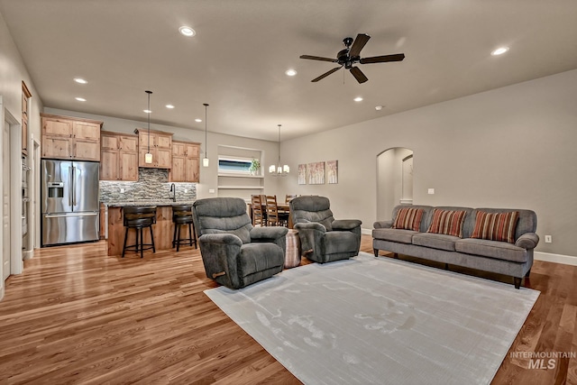 living area with recessed lighting, arched walkways, light wood-style flooring, and a ceiling fan