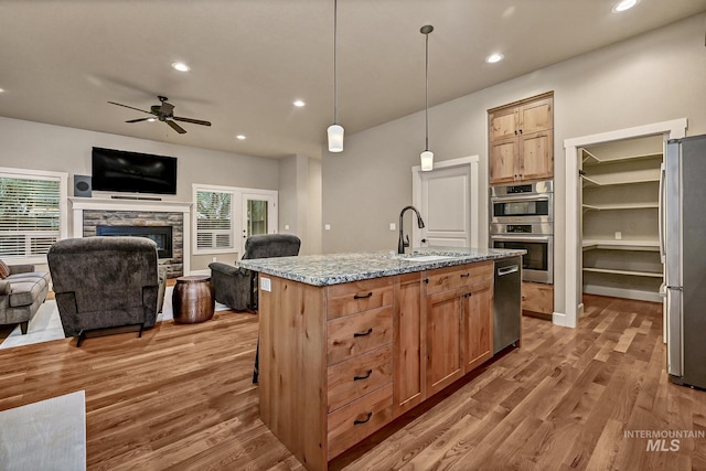 kitchen with a sink, wood finished floors, appliances with stainless steel finishes, and open floor plan