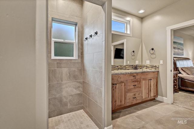 full bathroom featuring vanity, baseboards, tiled shower, ensuite bath, and recessed lighting