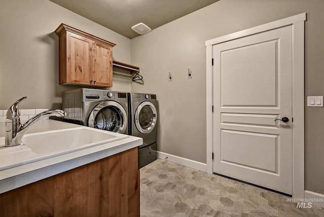 laundry room with a sink, baseboards, cabinet space, and independent washer and dryer