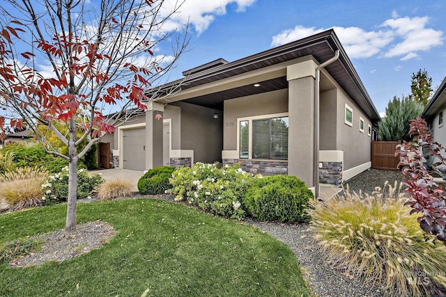 view of front of home featuring fence, stucco siding, a front lawn, a garage, and stone siding