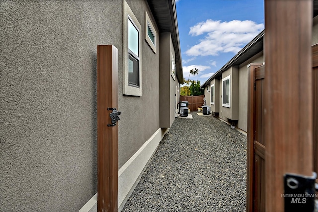 view of side of home featuring stucco siding and fence