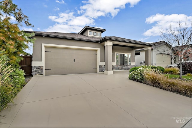 prairie-style house featuring fence, stucco siding, concrete driveway, a garage, and stone siding