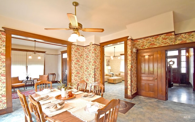 dining space with dark carpet and ceiling fan with notable chandelier